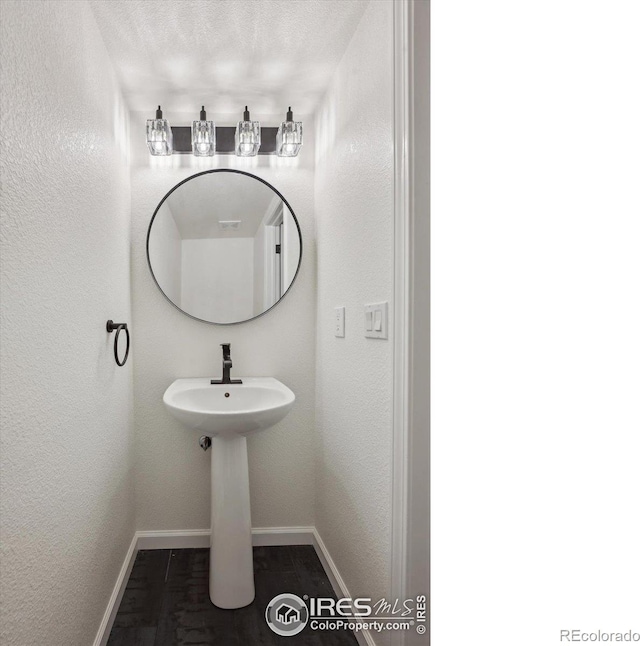 bathroom with a textured wall and baseboards