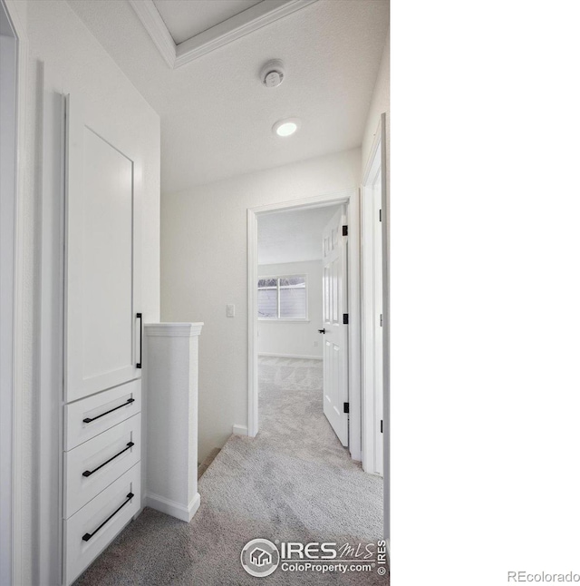 hallway featuring light carpet, an upstairs landing, and baseboards