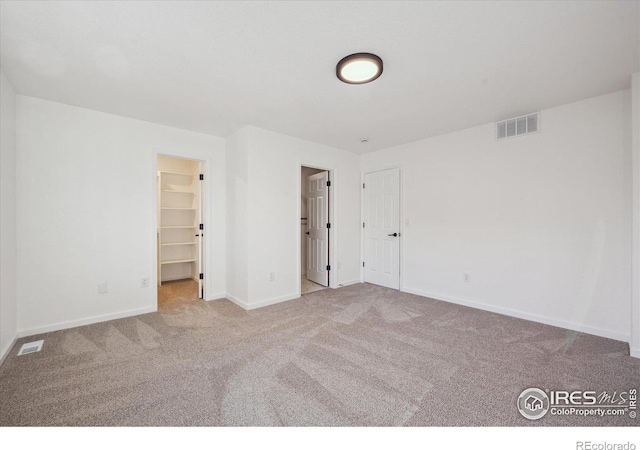 unfurnished bedroom featuring visible vents, light carpet, and baseboards