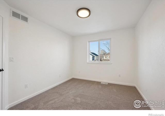 unfurnished room with carpet, visible vents, and baseboards