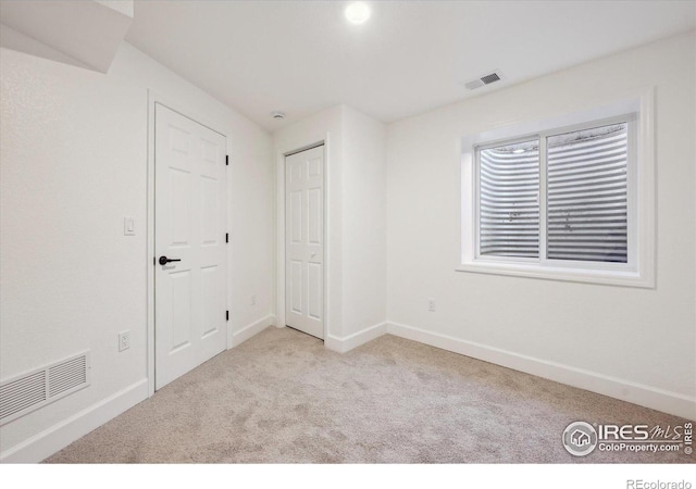 spare room featuring light carpet, visible vents, and baseboards