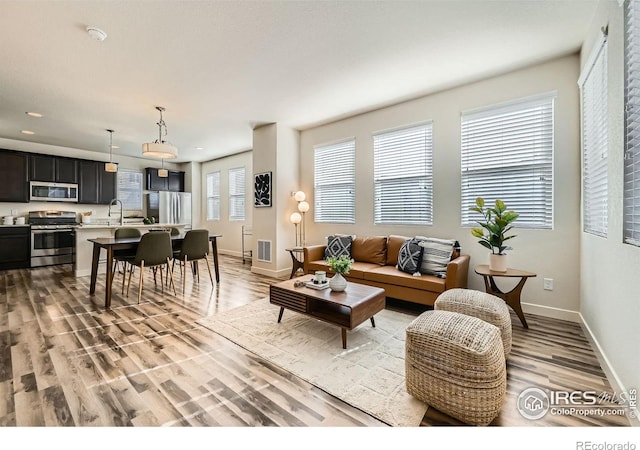 living room featuring recessed lighting, visible vents, light wood-style flooring, and baseboards