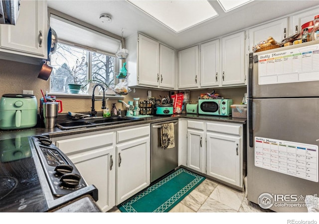 kitchen featuring stainless steel appliances, dark countertops, and white cabinets