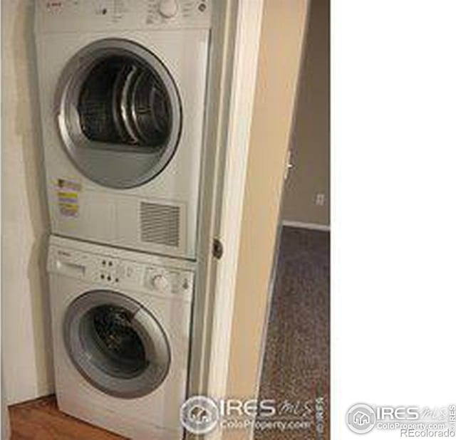 clothes washing area featuring stacked washing maching and dryer and laundry area