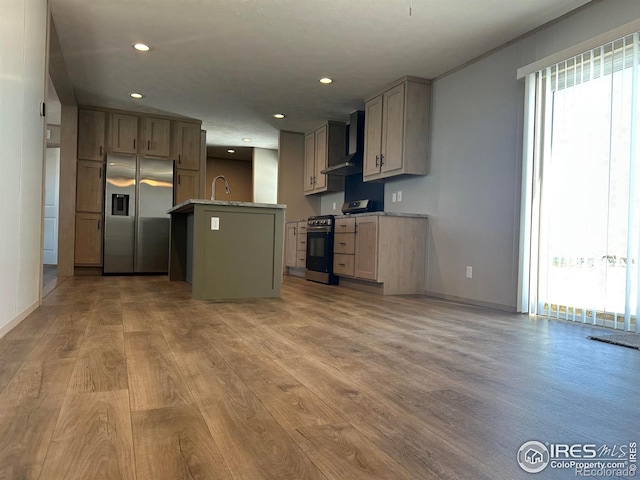 kitchen featuring recessed lighting, a sink, appliances with stainless steel finishes, wall chimney range hood, and light wood finished floors