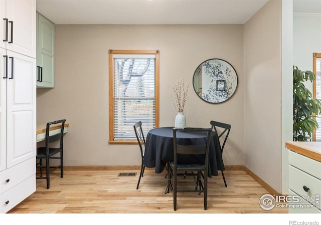 dining room featuring baseboards, visible vents, and light wood finished floors