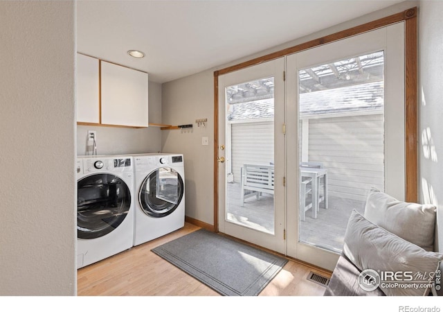 laundry room with light wood-type flooring, cabinet space, visible vents, and washer and dryer