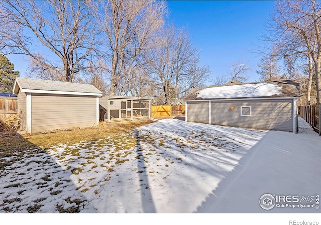 yard covered in snow featuring fence and an outbuilding