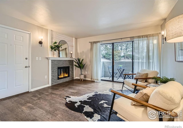 living room with a glass covered fireplace, wood finished floors, and baseboards