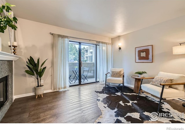 living area featuring dark wood-style flooring, a glass covered fireplace, and baseboards