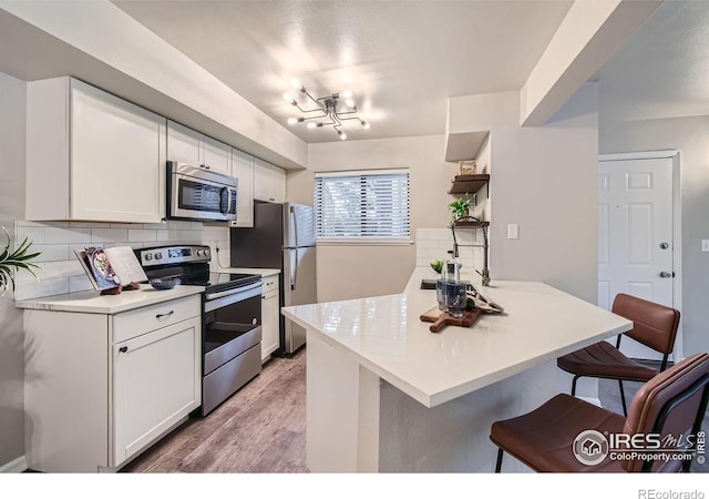 kitchen featuring light countertops, appliances with stainless steel finishes, a breakfast bar, and white cabinets