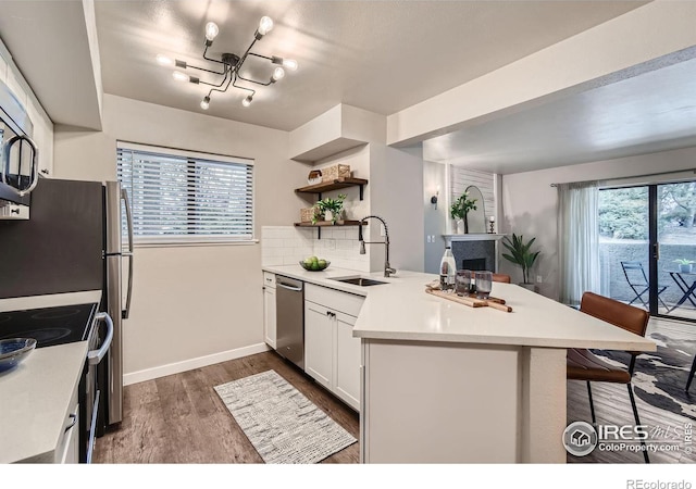 kitchen featuring a peninsula, a breakfast bar, range with electric cooktop, a sink, and light countertops