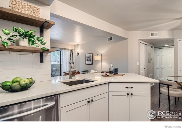 kitchen featuring light countertops, stainless steel dishwasher, white cabinetry, open shelves, and a sink