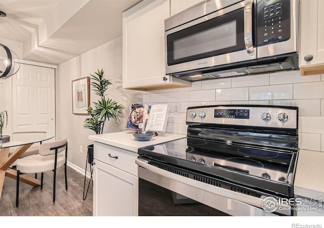 kitchen with appliances with stainless steel finishes, light countertops, light wood finished floors, and white cabinetry