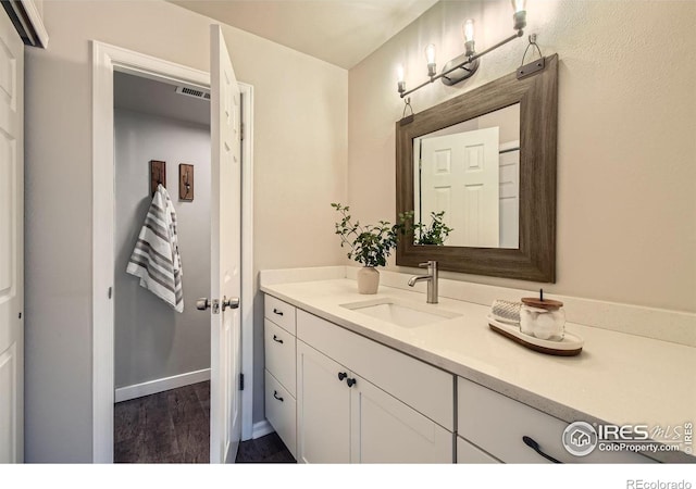 bathroom featuring visible vents, vanity, baseboards, and wood finished floors