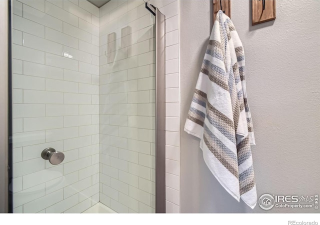 full bath featuring a textured wall and a tile shower