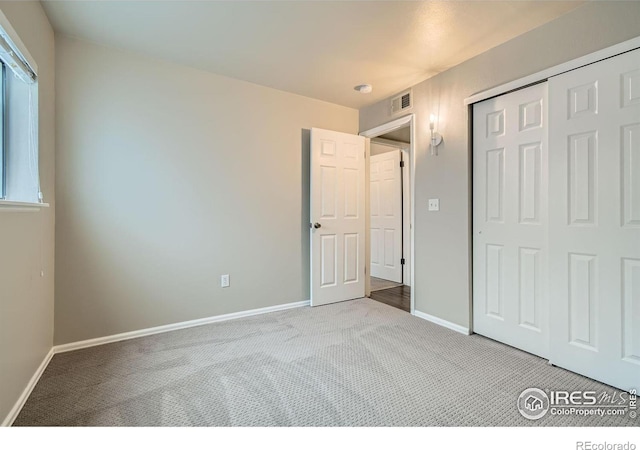 unfurnished bedroom featuring baseboards, a closet, visible vents, and light colored carpet