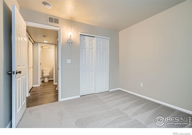 unfurnished bedroom featuring light carpet, a closet, visible vents, and baseboards