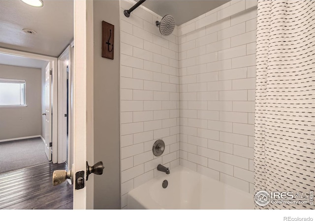 bathroom with wood finished floors, bathtub / shower combination, and baseboards