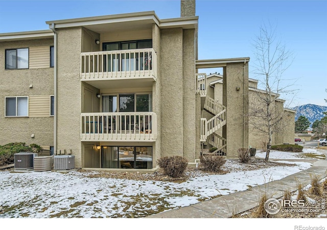 snow covered property with cooling unit and a mountain view