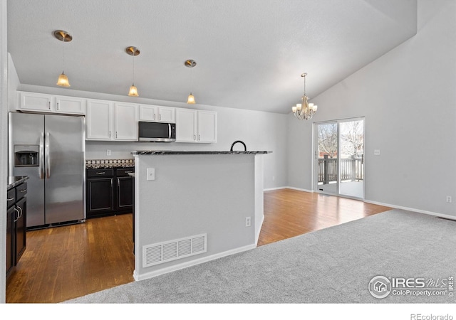 kitchen with dark countertops, white cabinetry, stainless steel appliances, and open floor plan