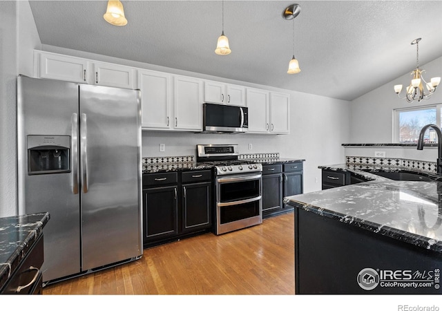 kitchen featuring stainless steel appliances, a sink, white cabinets, and pendant lighting