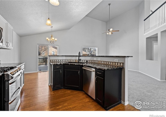 kitchen with hanging light fixtures, dark cabinets, appliances with stainless steel finishes, and a sink