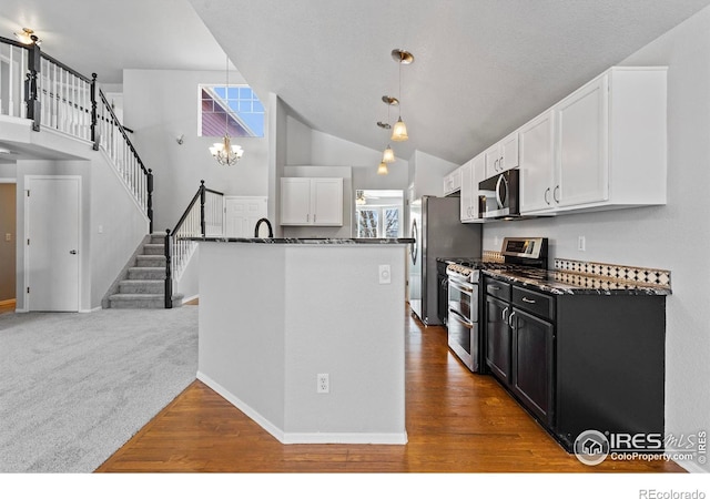 kitchen with appliances with stainless steel finishes, wood finished floors, decorative light fixtures, dark cabinetry, and white cabinetry