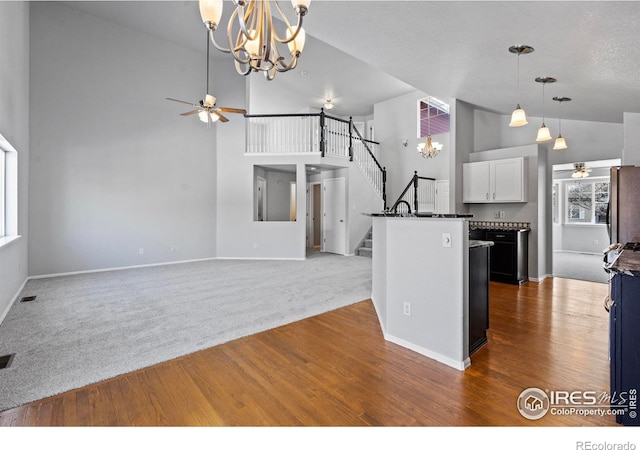 kitchen with a center island, dark countertops, hanging light fixtures, open floor plan, and white cabinets