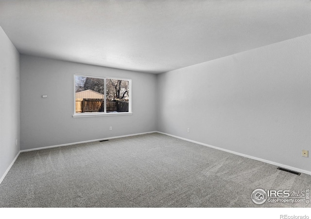 spare room featuring baseboards, visible vents, and carpet flooring