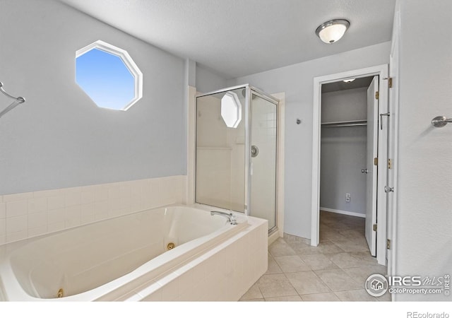 bathroom featuring a textured ceiling, tile patterned flooring, a spacious closet, a jetted tub, and a shower stall