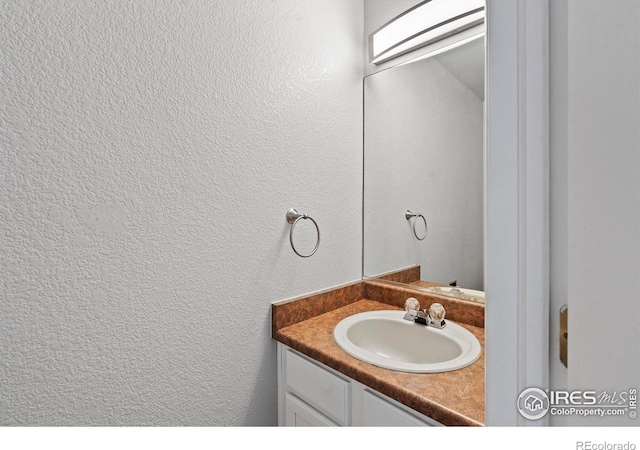 bathroom with a textured wall and vanity