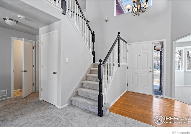 foyer entrance with an inviting chandelier, stairway, arched walkways, and light colored carpet