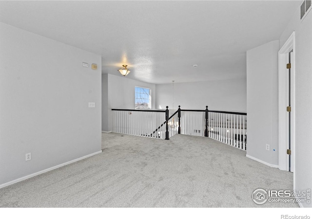 carpeted spare room with visible vents and baseboards