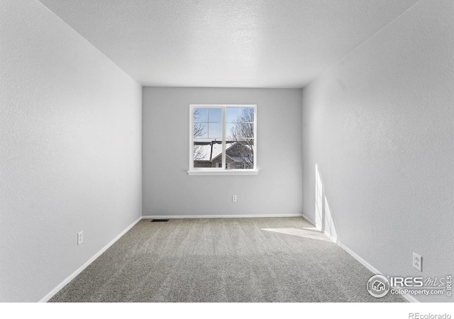 empty room featuring light colored carpet, visible vents, a textured wall, and a textured ceiling