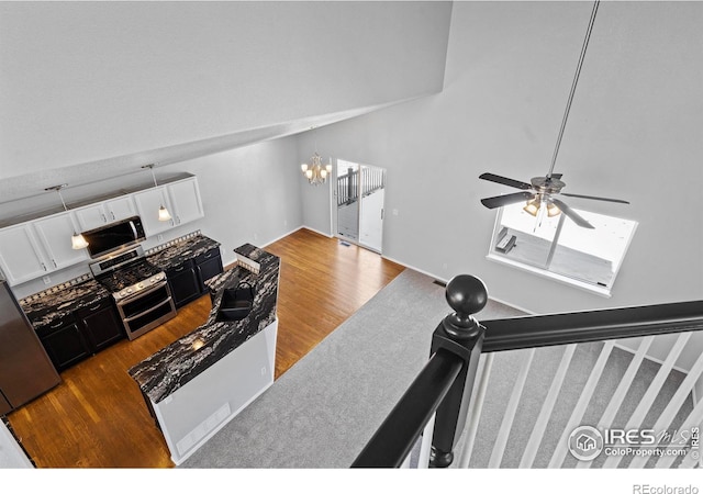 living room with stairs, wood finished floors, and ceiling fan with notable chandelier