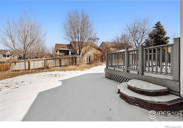 yard layered in snow featuring a deck and a fenced backyard