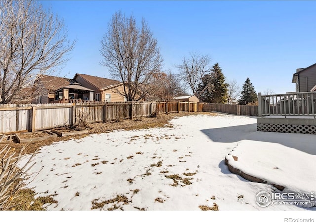 yard covered in snow featuring a fenced backyard and a wooden deck