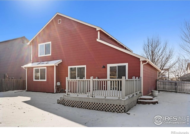 rear view of house with fence and a deck