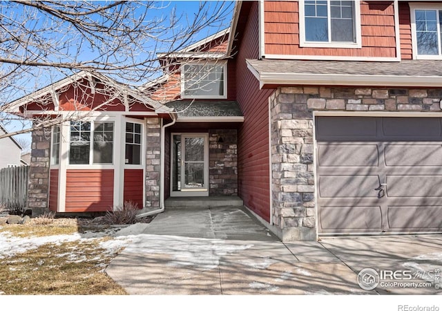 view of exterior entry featuring a garage, stone siding, and roof with shingles