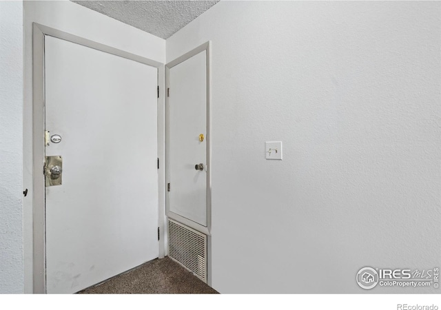 doorway featuring carpet, visible vents, and a textured ceiling