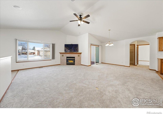 unfurnished living room with arched walkways, light colored carpet, lofted ceiling, and a tiled fireplace