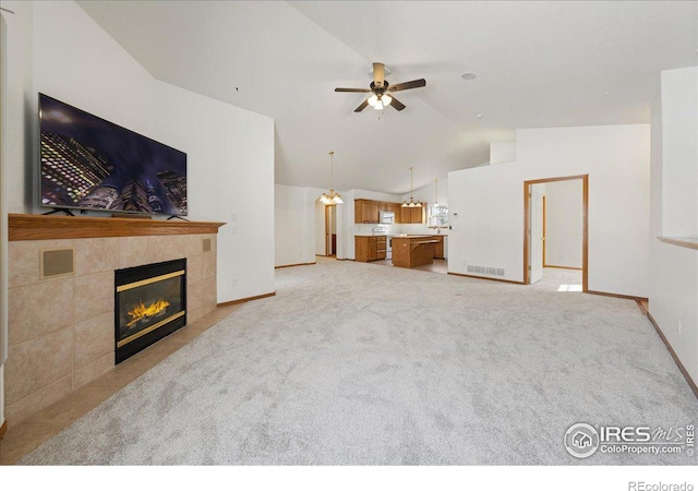 living area with a fireplace, light colored carpet, visible vents, a ceiling fan, and vaulted ceiling