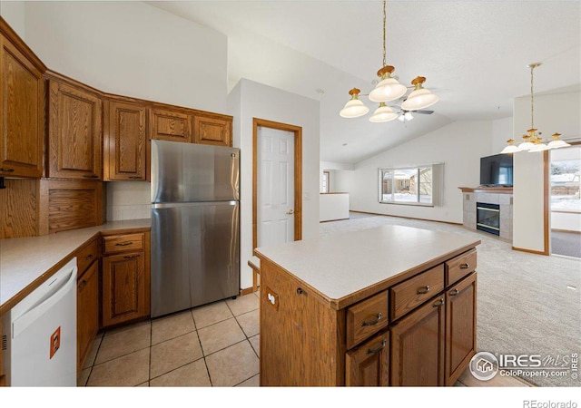 kitchen featuring brown cabinetry, decorative light fixtures, freestanding refrigerator, white dishwasher, and light countertops