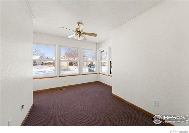 spare room with visible vents, dark carpet, baseboards, and ceiling fan