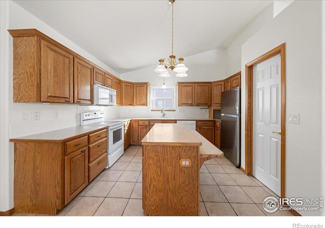 kitchen with light countertops, white appliances, brown cabinetry, and a kitchen island