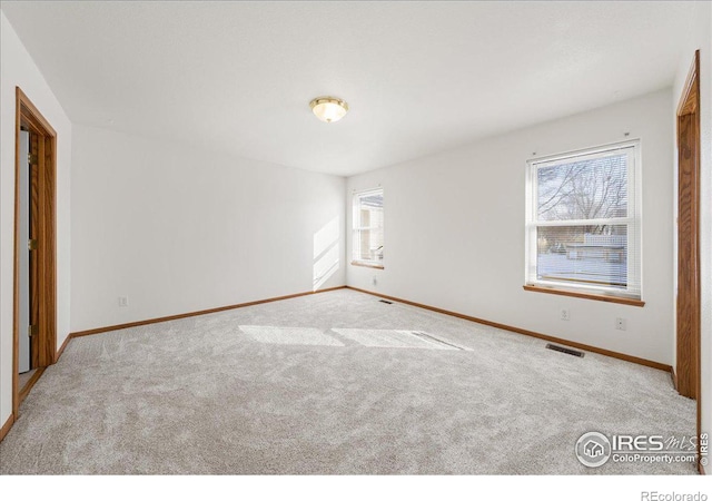 empty room featuring baseboards, visible vents, and light colored carpet