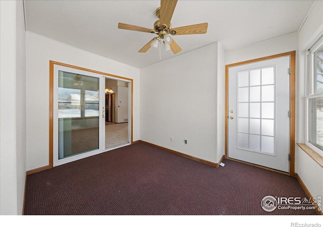 unfurnished room with dark colored carpet, ceiling fan, and baseboards