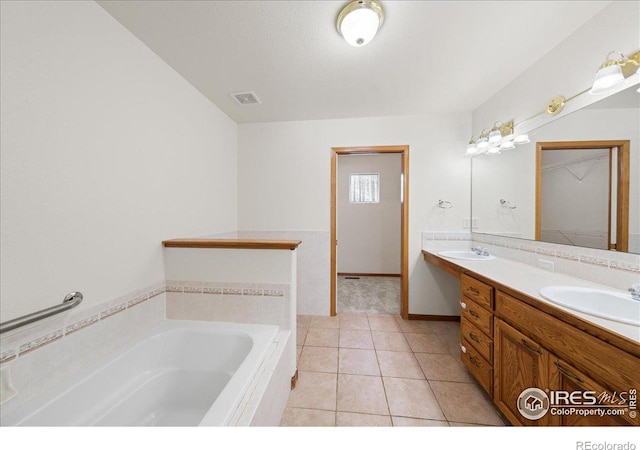 bathroom with a garden tub, tile patterned flooring, a sink, visible vents, and double vanity