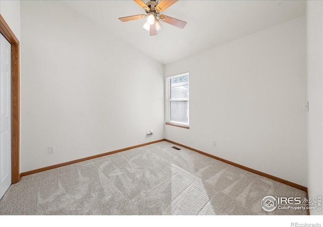 carpeted spare room featuring lofted ceiling, visible vents, ceiling fan, and baseboards